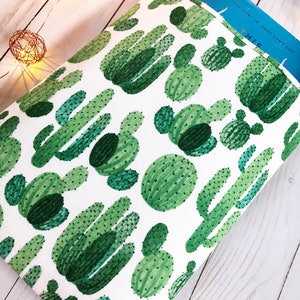 May include: A white book sleeve with a green cactus pattern. The sleeve has a blue book inside with the text "This went in four came out".