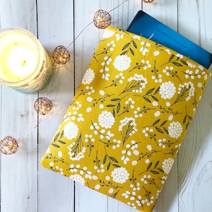 Könnte beinhalten: Eine gelbe Buchhülle mit einem weißen Blumenmuster. Die Hülle ist aus Stoff und hat ein Buch darin.