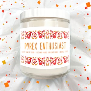 May include: A white glass candle jar with a red and gold patterned label. The label reads "PYREX ENTHUSIAST" and "SCENT: VANILLA SUGAR | 8 OZ HAND POURED SOY BLEND CANDLE | ANIMACY STORE".