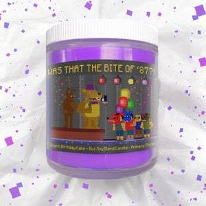 May include: Purple soy blend candle with a graphic of pixelated characters from the video game Five Nights at Freddy's. The text on the candle reads "Was that the bite of '87?!". The candle is 8 ounces and has a birthday cake scent.