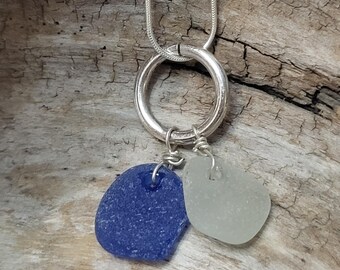 May include: A silver necklace with a circle pendant and two sea glass charms, one blue and one white.