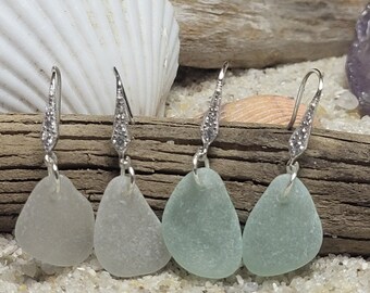 May include: Four pairs of sea glass earrings with silver hooks. The sea glass is in shades of light blue and green.