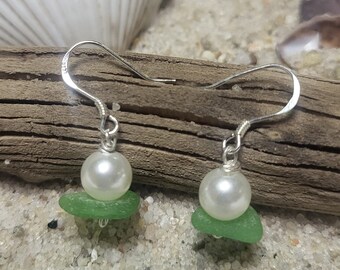 May include: A pair of silver earrings with a white pearl and a green sea glass accent.