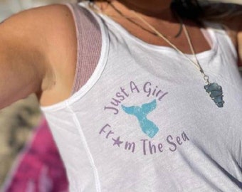 May include: White tank top with a purple and blue graphic that says "Just a Girl From The Sea" with a mermaid tail design.