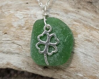 May include: A green sea glass pendant necklace with a silver four-leaf clover charm.