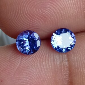 May include: Two round, faceted, blue gemstones. The gemstones are set in a bezel setting and have a high polish.