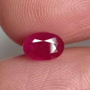 May include: A vibrant red oval-shaped gemstone with a faceted cut.