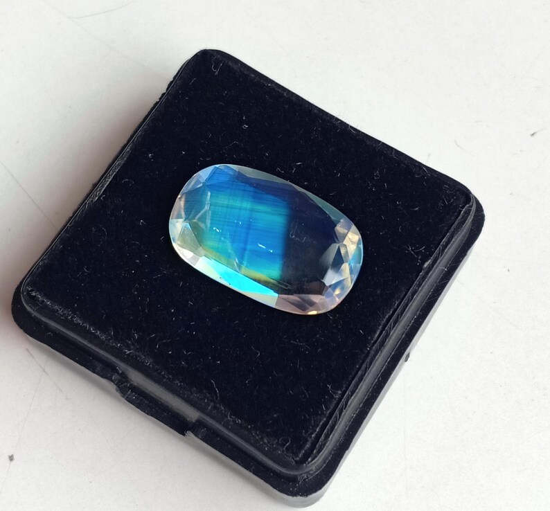 May include: A blue and green iridescent gemstone in a black velvet display box.