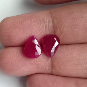 Puede incluir: Dos piedras preciosas de rubí talladas en forma de pera, de color rojo intenso.