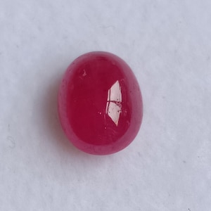 Könnte beinhalten: Ein lebhafter, ovaler Edelstein in Pink mit einer glatten, polierten Oberfläche.