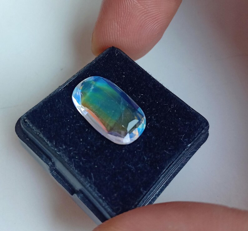 May include: A oval-shaped iridescent gemstone with blue, green, and purple hues, set in a black velvet display box.