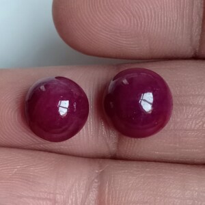 May include: Two round, red gemstones with a smooth, polished surface.
