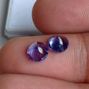 May include: Two round, purple gemstones with a shiny, polished finish.