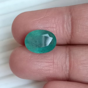 May include: A vibrant green emerald gemstone with a faceted oval shape.