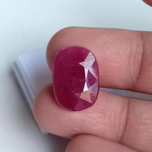 Puede incluir: Una piedra preciosa de rubí rojo oscuro con forma ovalada facetada.
