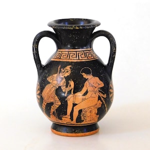 Könnte beinhalten: Eine schwarze Keramik-Amphore mit zwei Henkeln und einem breiten Rand. Der Körper ist mit orangefarbenen Figuren im klassischen Stil verziert, die eine stehende und eine sitzende Person zeigen, umrahmt von einem geometrischen Mäander-Muster.