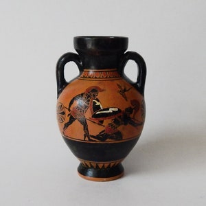 May include: A small black and orange ceramic vase with a scene of two Greek warriors painted on the side.