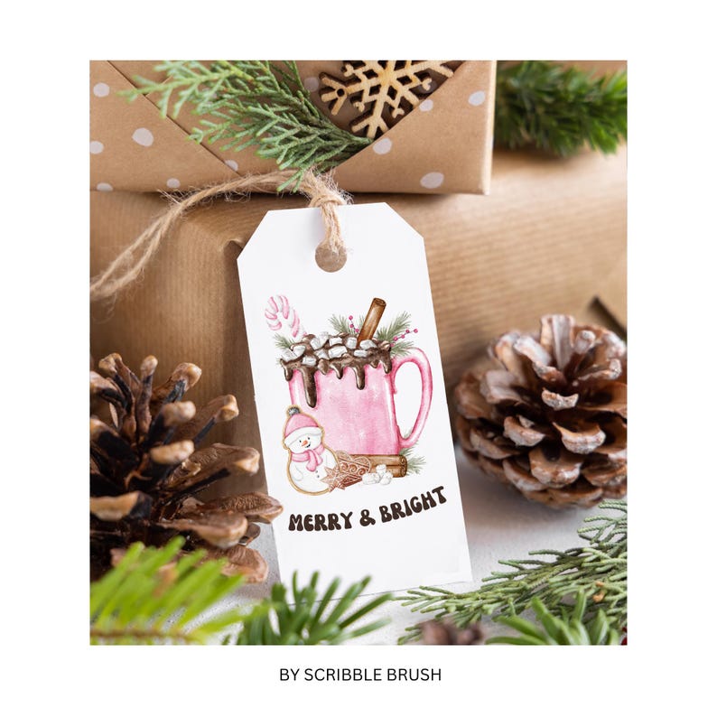 May include: A white gift tag with a watercolor illustration of a pink mug filled with hot chocolate, marshmallows, and a candy cane. The mug is decorated with a snowman and the text "Merry & Bright".