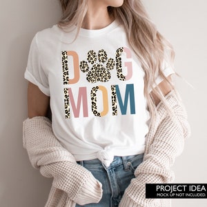 May include: White t-shirt with a leopard print paw print and the text "Dog Mom" in colorful letters.