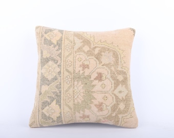 May include: A beige throw pillow with a floral pattern in shades of green, brown, and pink. The pillow has a fringe border.