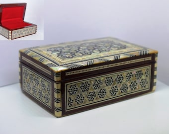 Peut inclure: Une boîte en bois avec un intérieur rouge et des motifs complexes en nacre incrustés. La boîte est fermée et a une forme rectangulaire.