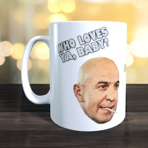 Op de afbeelding: Witte keramische mok met een zwart-witte afbeelding van een man met de tekst "Who loves ya, baby?" erop gedrukt.