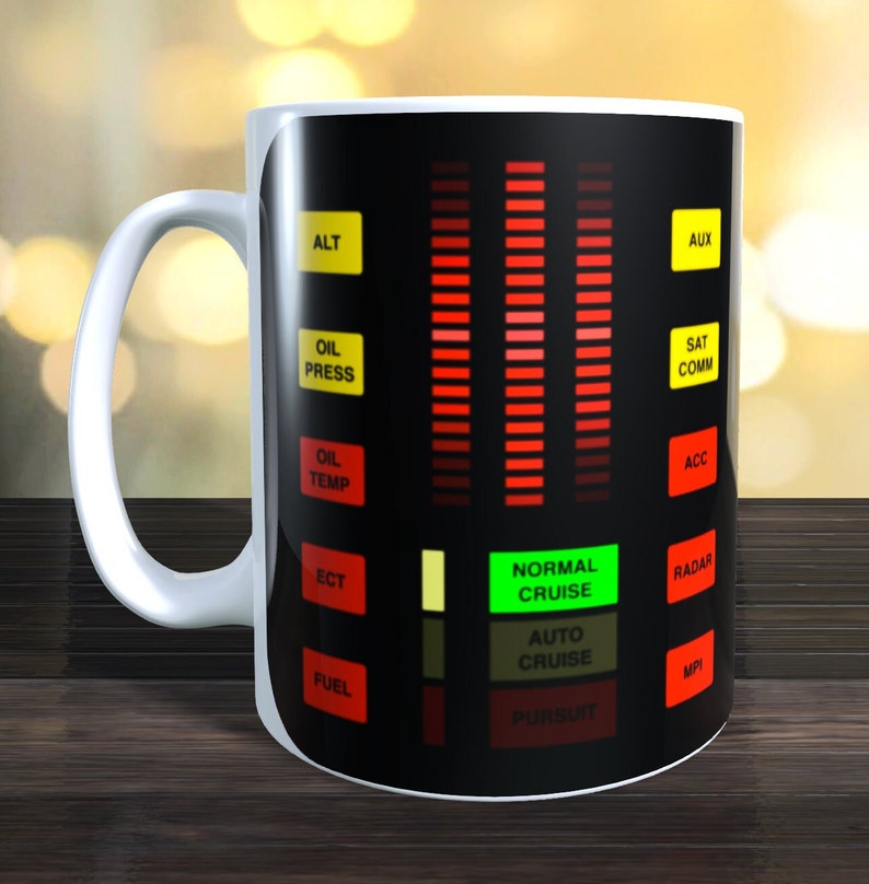 May include: A white ceramic mug with a black and red design that resembles the dashboard of a car. The design includes a series of red lights, a green light that says "NORMAL CRUISE", and various labels such as "ALT", "OIL PRESS", "OIL TEMP", "ECT", "FUEL", "AUX", "SAT COMM", "ACC", "RADAR", "MPI", "AUTO CRUISE", and "PURSUIT".