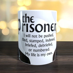 May include: White ceramic mug with black text that reads "the prisoner I will not be pushed, filed, stamped, indexed, briefed, debriefed, or numbered. My life is my own."