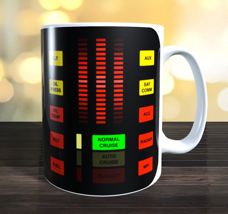May include: A white ceramic mug with a black design of a car dashboard with red and green lights. The dashboard has text that reads "ALT", "AUX", "OIL PRESS", "SAT COMM", "OIL TEMP", "ACC", "ECT", "FUEL", "NORMAL CRUISE", "AUTO CRUISE", "PURSUIT", "RADAR", and "MPI".