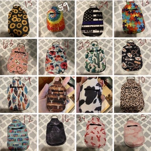 Könnte beinhalten: Zwölf verschiedene Handdesinfektionsmittel-Halter mit verschiedenen Mustern und Designs. Die Halter sind aus Neopren und haben einen Reißverschluss. Die Muster umfassen Sonnenblumen, Batik, eine amerikanische Flagge, ein Puzzle, Blumen, Kakteen, Federn, ein Reh, eine Kuh, Leopardenmuster, einen Wohnwagen, ein dunkelgraues Design, rosa Bänder und Marmor.