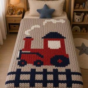 Könnte beinhalten: Eine beige Strickdecke mit einem roten und marineblauen Zugmuster. Die Decke hat unten einen marineblauen Zaun und weißen Rauch. Die Decke liegt auf einem Holzbett mit einem sternförmigen Kissen.