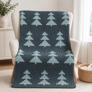 May include: A dark charcoal gray chunky knit throw blanket featuring a repeating pattern of light mint green stylized pine trees. The blanket is constructed with a thick, textured yarn weave and displays a consistent grid of tree motifs throughout.