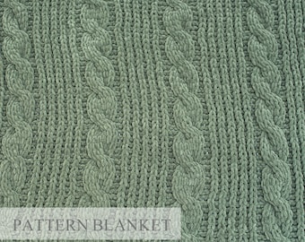 May include: A green cable knit throw blanket with a soft, fuzzy texture. The blanket has a repeating pattern of woven cables.