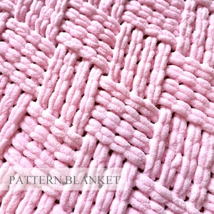 May include: A light pink blanket featuring a thick, chunky, woven yarn texture with a repeating basketweave pattern. The surface is soft and plush, with the text PATTERN BLANKET clearly visible in a white rectangular overlay at the bottom center.