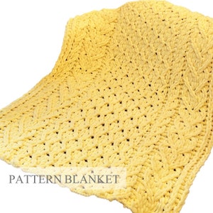 Peut inclure: Une couverture en tricot épais jaune vif présentant un motif de torsades texturé sur tout le tissu. La couverture a une apparence douce et épaisse avec un design tressé répétitif. Le texte PATTERN BLANKET est visible en bas.