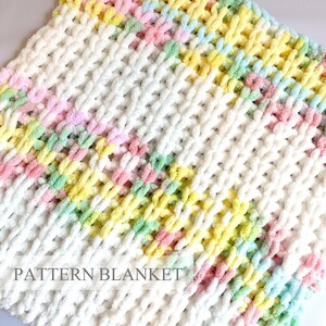 Op de afbeelding: Een grof gebreide deken van zacht, getextureerd garen in een pastelkleurenpalet van wit, lichtgeel, lichtroze en mintgroen. De stof heeft een zichtbare lussteekconstructie. De tekst PATTERN BLANKET is in het grijs op de deken gedrukt.