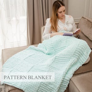 Puede incluir: Una manta de punto grueso en un suave color verde menta con un patrón de tejido de cesta texturizado. La manta está extendida sobre una superficie e incluye el texto PATTERN BLANKET superpuesto en un recuadro blanco en la parte inferior.