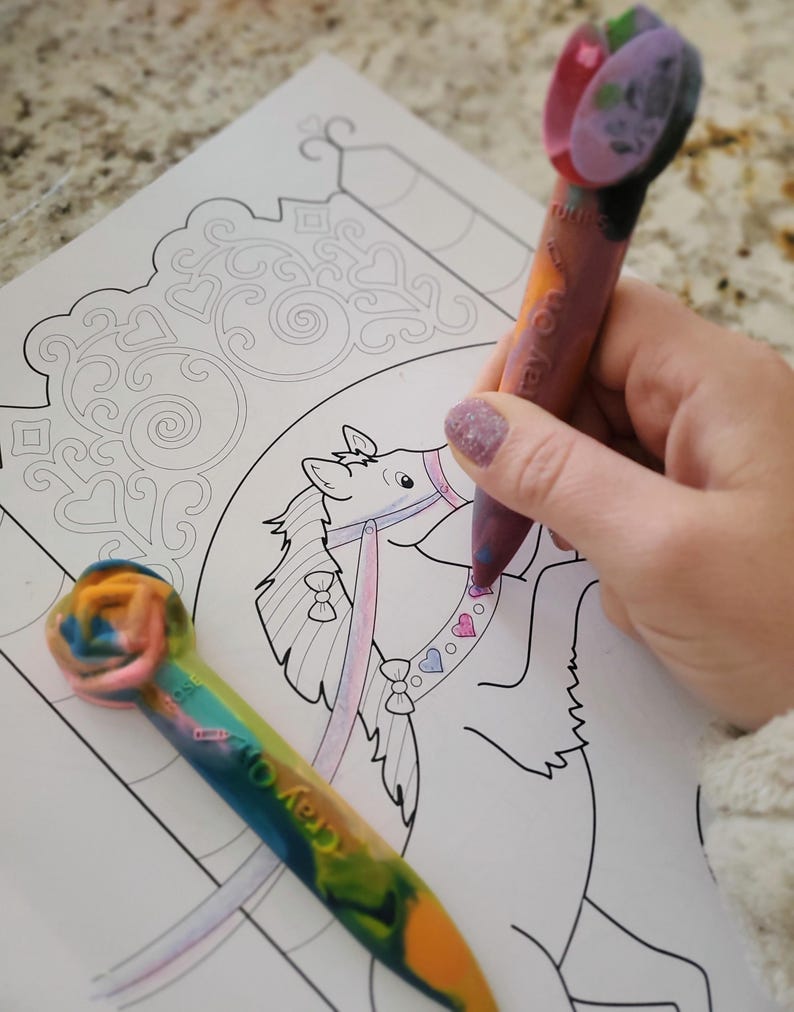 May include: A close-up of a coloring page featuring a cartoon horse on a carousel. The horse is being colored in with a rainbow crayon and a pink and purple crayon. The text "Crayola" is visible on the rainbow crayon.