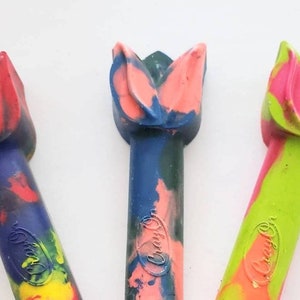 May include: Three colorful crayon shaped like tulips. The crayons are blue, green, and orange with red, pink, and yellow accents. The crayons are labeled "Crayola".