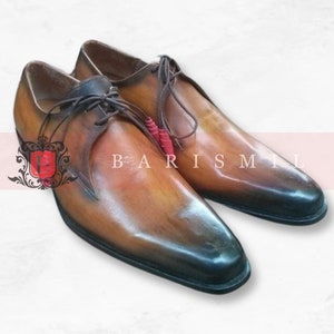 May include: A pair of brown leather lace-up shoes with a pointed toe. The shoes have a dark brown leather sole and a light brown leather upper. The shoes are tied with brown laces.