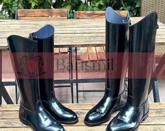 May include: Two pairs of black leather riding boots with a shiny finish. The boots have a zipper on the back and a buckle on the side.
