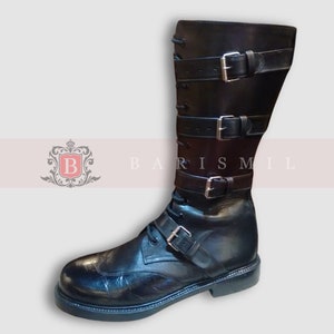 Puede incluir: Botas de cuero negro con múltiples hebillas y un cierre de cordones en la parte delantera. Las botas tienen una punta puntiaguda y una suela gruesa.