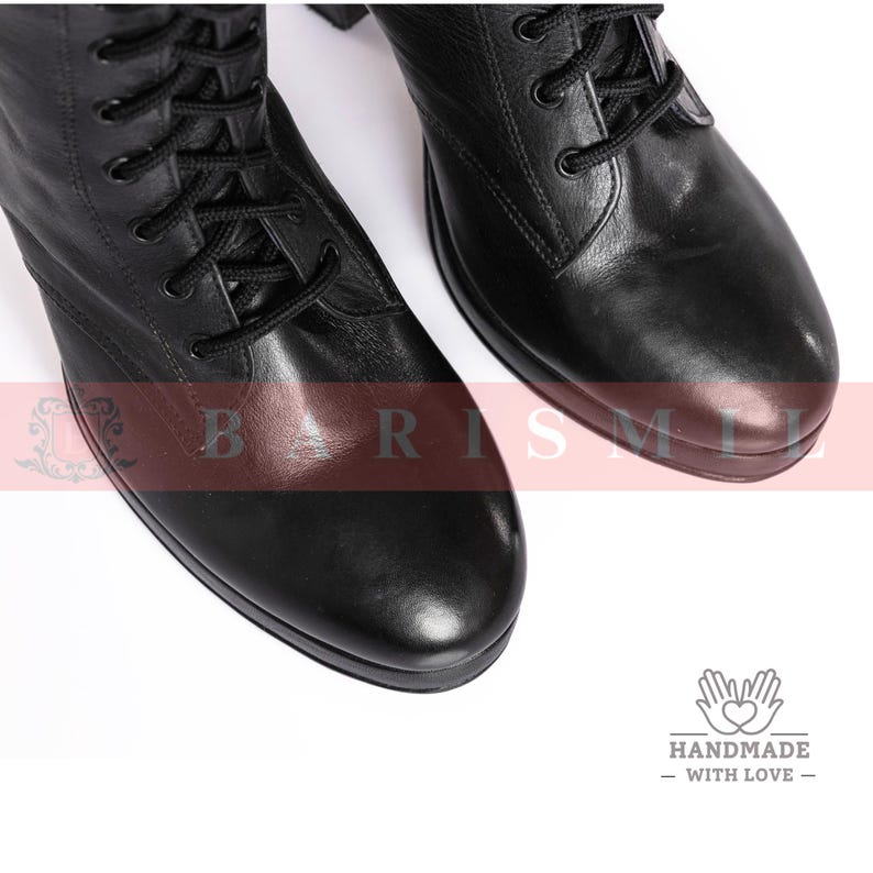 May include: Close-up of two black leather combat boots with black laces. The boots have a rounded toe and a sturdy sole. The image is on a white background. The boots are handmade with love.