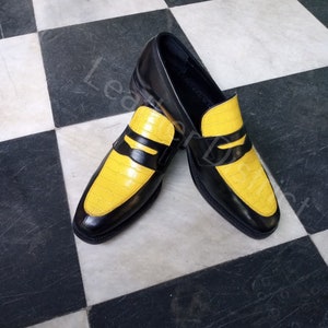 May include: A pair of black leather loafers with yellow leather accents. The loafers have a pointed toe and a slip-on design.