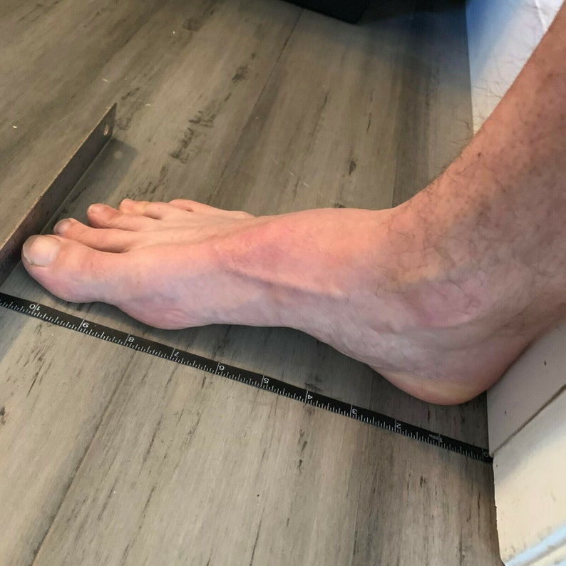 May include: A close-up of a person's foot measuring 40.6 cm long on a black ruler.