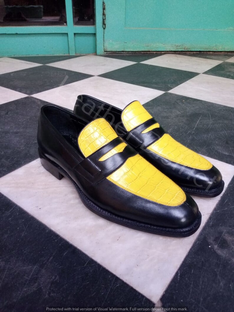 May include: A pair of black leather loafers with yellow leather accents. The loafers have a pointed toe and a black rubber sole.