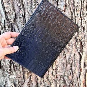 May include: A black leather clutch with a crocodile embossed pattern.