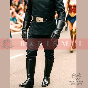 Puede incluir: Un uniforme negro con cinturón y guantes a juego. El uniforme incluye botas de montar negras. La imagen también muestra a una persona con un disfraz de Wonder Woman en el fondo.