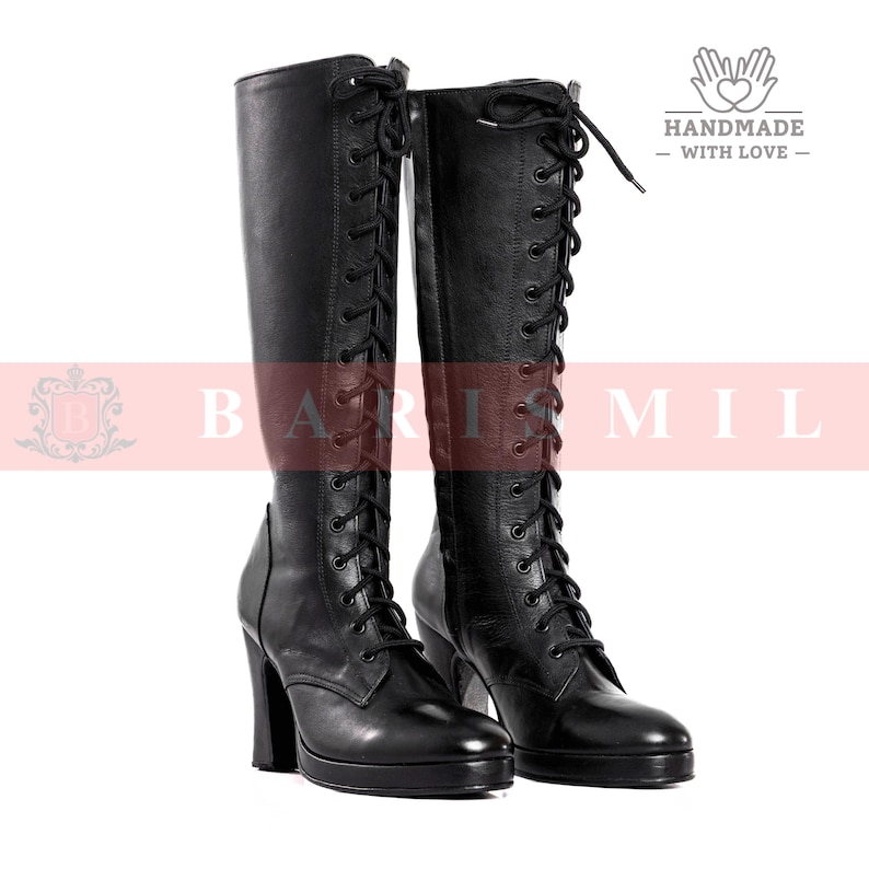 May include: A pair of black leather knee-high boots with lace-up detailing. The boots have a high heel and a rounded toe. The image also includes the text "BARI MIL" and "HANDMADE - WITH LOVE -."