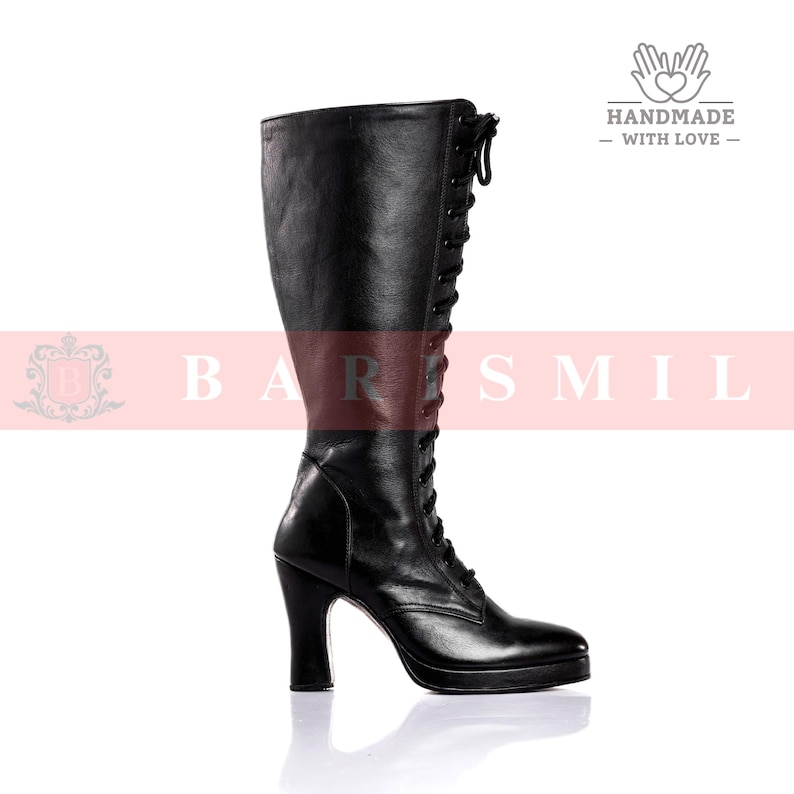May include: A black knee-high boot with a lace-up design and a high heel. The boot has a rounded toe and a platform sole. The image is set against a white background.
